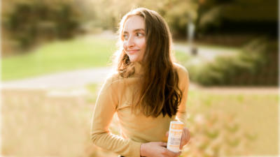 woman outside holding schmidt's ylang-ylang and calendula deodorant